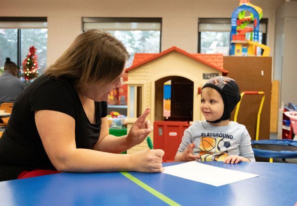 Teacher showing young boy sign language