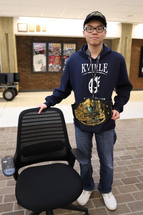Kenny Nguyen, winner of esports competition, with championship belt and Steelcase gaming chair